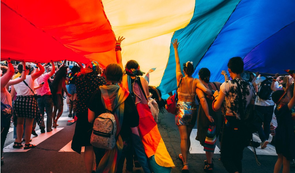Pride Street event with people holding up a big rainbow flag
