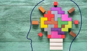 The outline of a head drawn on a table containing multicoloured blocks to represent the brain in a lightbulb shape