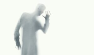 shadow of a man putting hand up against frosted glass