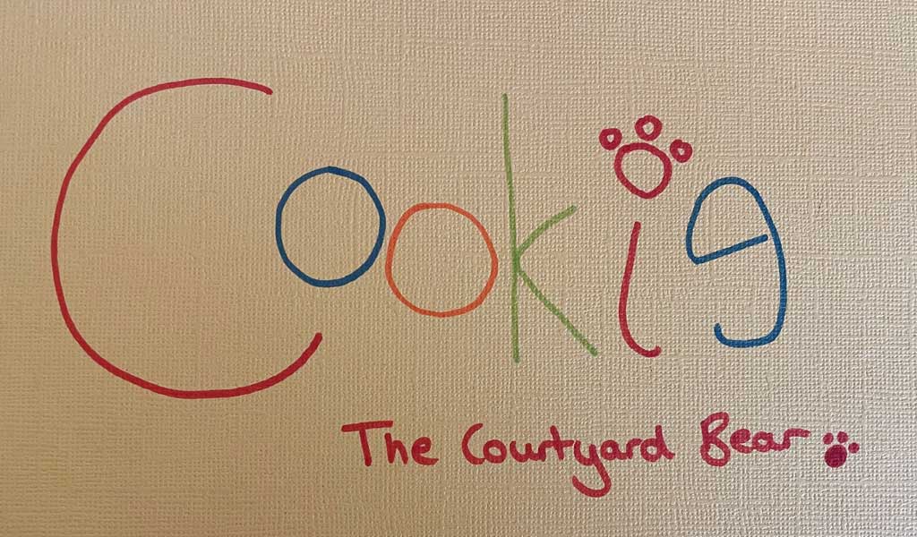 Cookie The Courtyard Bear's signature written in rainbow colours