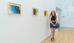 Rowan Bretherton stood next to art at the exhibition 