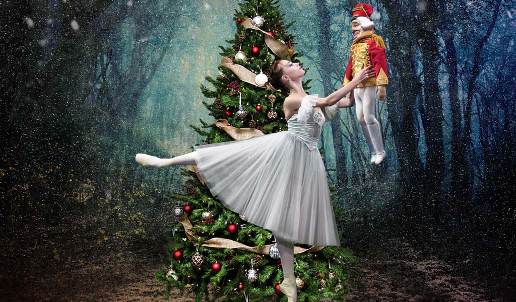 The Nutcracker - ballerina dancing with a nutcracker toy in front of a Christmas tree