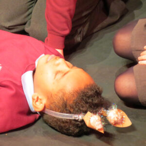 A child lying on the floor wearing fake animal ears on a head band