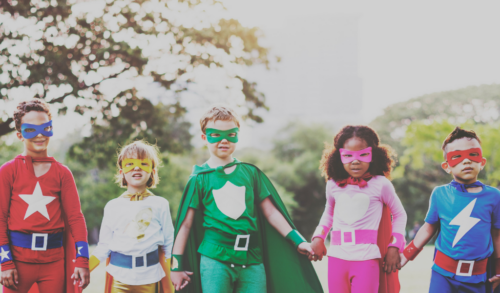 Children in superhero costumes holding hands in a line