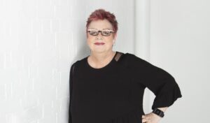 Jo Brand: Born Lippy Image - Jo Brand stands leaning against a wall whilst looking at the camera