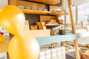 The Courtyard Shop: A wooden stand with gifts on the shelves and two gold balloons in the sunlight