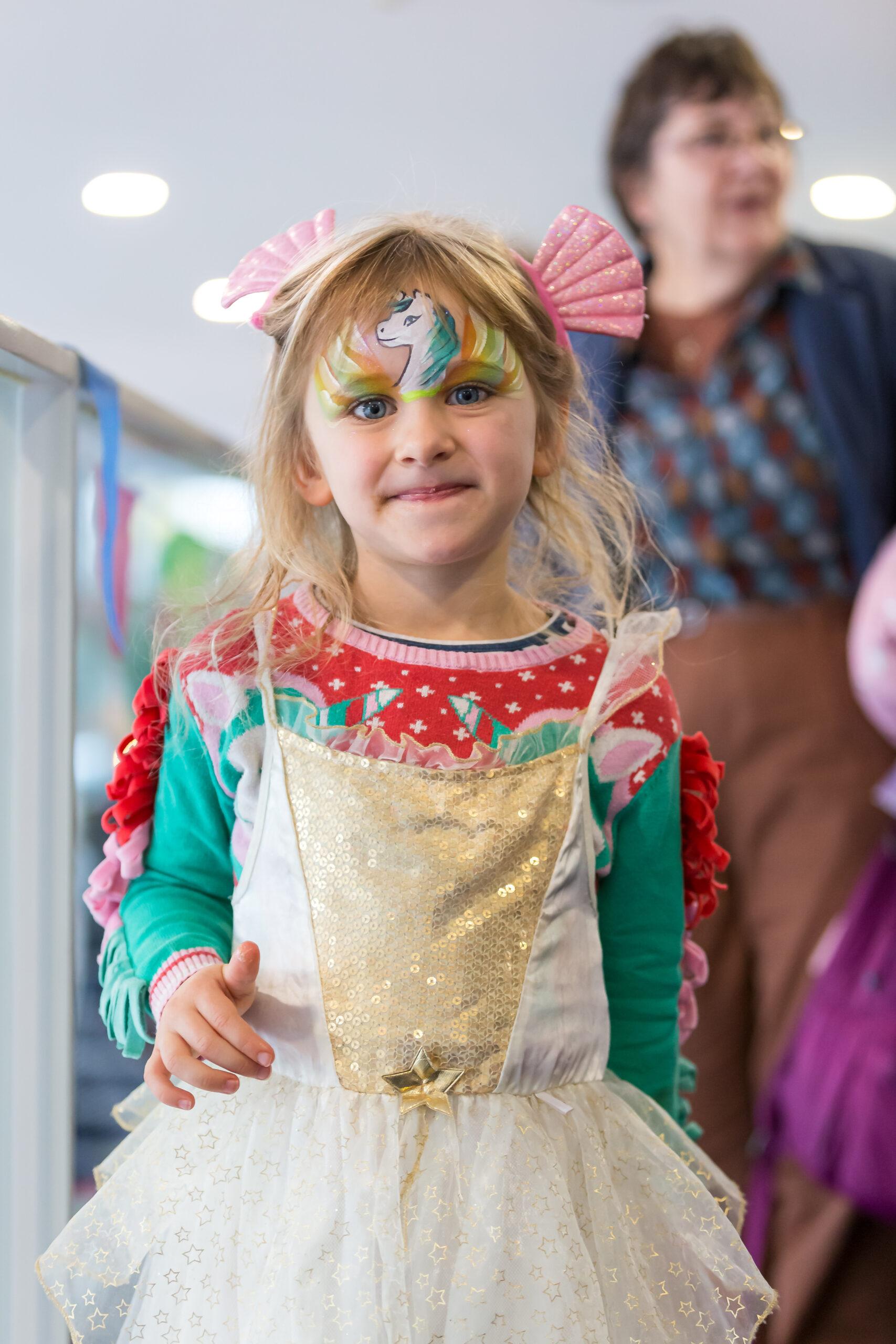 Family Festival: A little girl dressed in a princess costume smiling at the camera