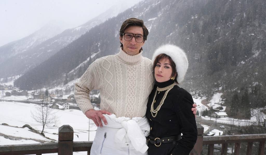 House of Gucci - A man and a woman in designer clothes stand arm in arm in front of a snow, mountainous backdrop