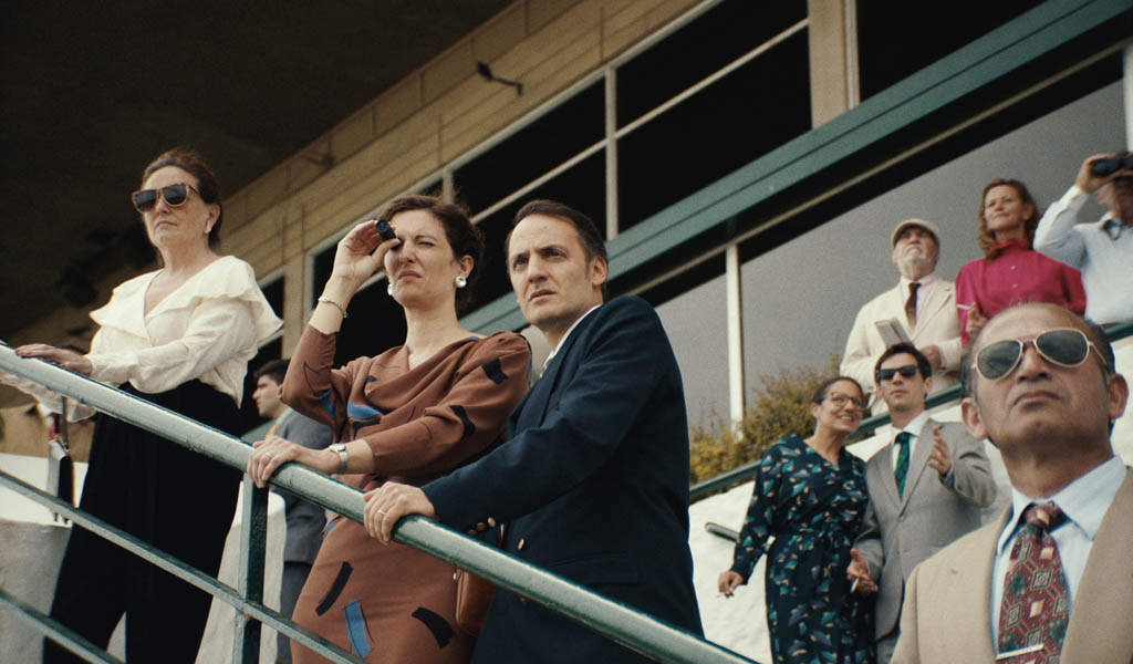 Multiple people stand on the stairs outdoors at the races