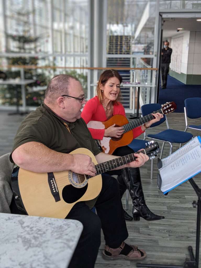 A man and a woman playing guitar at Cafe Muse at The Courtyard