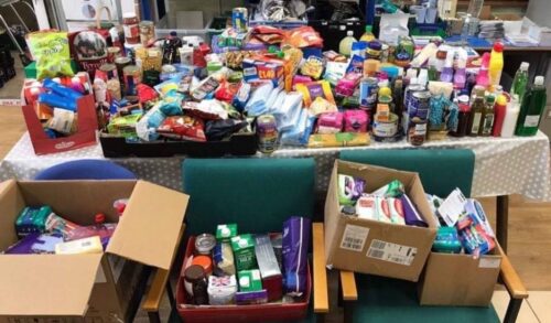 A large collection of donations are collected on a table at Hereford Food Bank