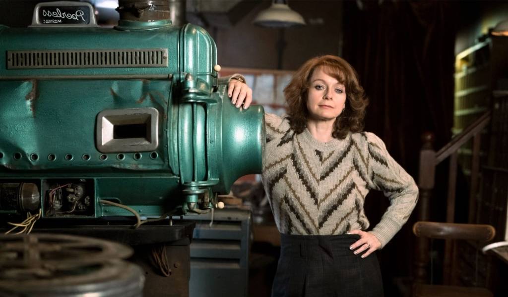 Samantha Morgan as Liz Evans leans against a 35mm projector