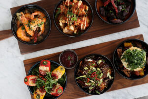 A selection of six tapas style dishes served across wooden boards