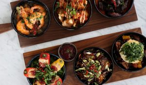 A selection of six tapas style dishes served across wooden boards