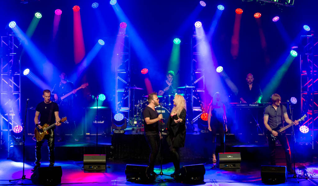 The band performing onstage under blue and pink lights