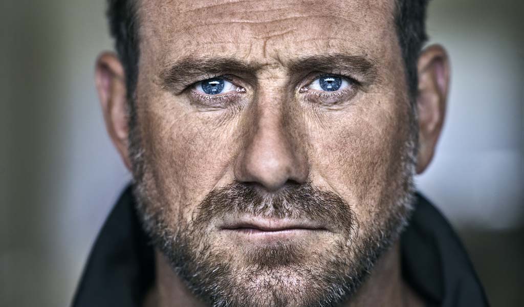 Jason Fox, a man in his 40;s with brown stubble frowns at the camera