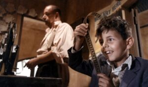 Cinema Paradiso, image - a young boy looks through a reel of 35mm film