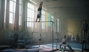 A gymnast swinging upside down on a beam