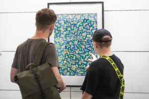 Image - Two people stand and look at a piece of artwork