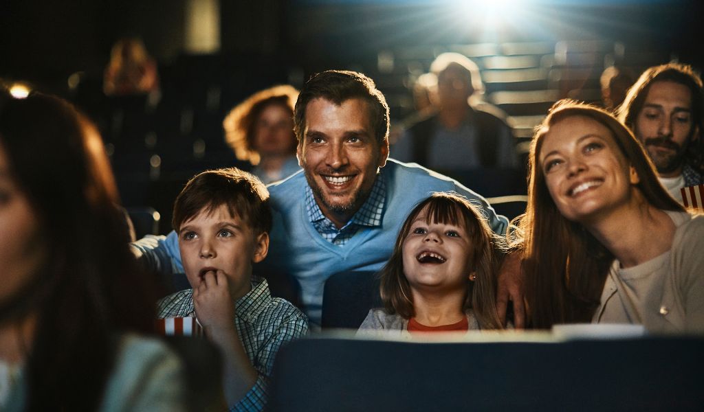 A man and woman sat in a cinema with their children looking in awe at the screen