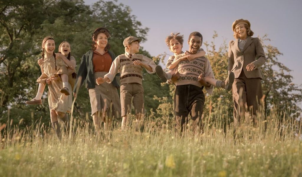 The Railway Children Return - A group of children run down a hill with long grass