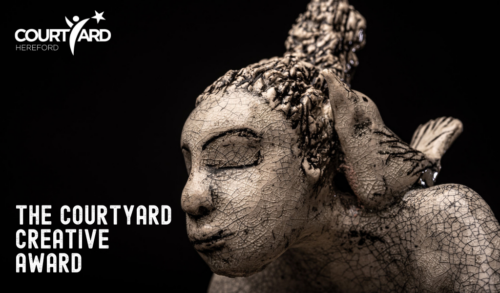 Black background with a sculpture of a face The courtyard Creative Award written next to it
