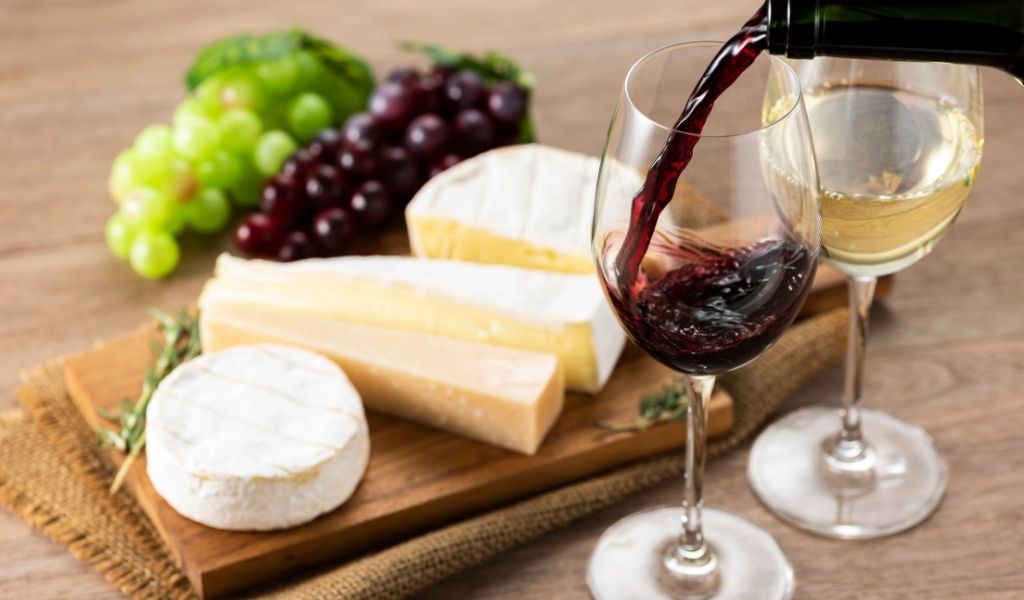 A cheese board with grapes and two glasses of wine