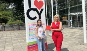 Kid Lit winner Daisy Fleetwood stood in front of The Courtyard being handed her prizes by a blonde woman wearing a bright red jumpsuit