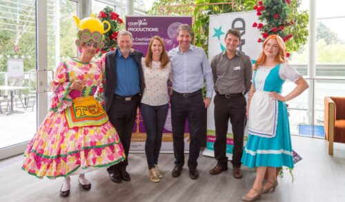 Panto launch two pantomime cast members stood with members of The Courtyard Board smiling