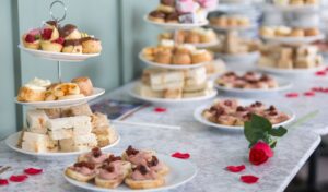 Afternoon tea ladid out on a white tablecloth next to a red rose