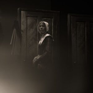 A black and white image of a girl wearing a white bonnet, looking concerned