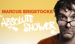 'Marcus Brigstocke Absolute Shower' written on a yellow background next to an image of Marcus Brigstocke who looks directly at the camera with water drops on his glasses