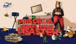 'Priscilla Queen of the Disaster' written next to a woman sat on the arm of a sofa wearing dungarees and a crown and holding a mug looking upwards. Next to her are various toys scattered around the sofa.