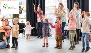 A room with toddlers, babies and parents and guardians dancing