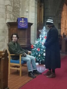 Two young adults perform in a church in front of a Christmas tree