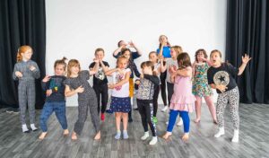 A group of children miming playing different musical instruments