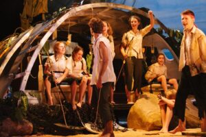 A group of young actors on stage, performing in Lord Of The Flies