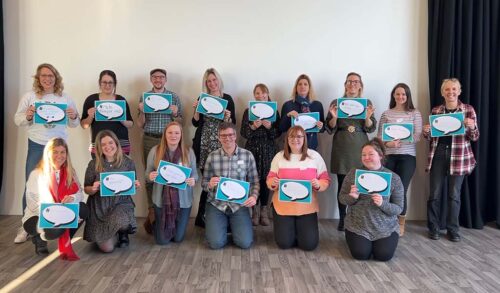 A group of teachers holding pieces of paper with speech bubbles on them In the speech bubbles they have written inspiring quotes about looking after your mental health