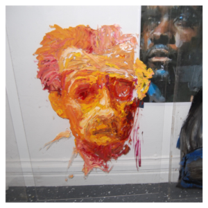 A photo of an orange portrait painting on a piece of glass.