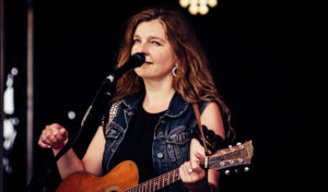 Jennifer Crook image: a close up of a woman singing holding a guitar