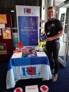 A man from the British Legion standing by an information desk smiling