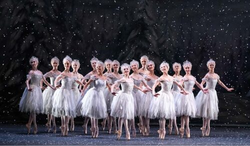 A group of ballerinas stood on stage Fake snow falls around them