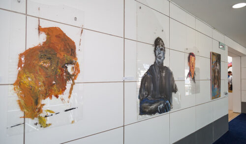 A photo of acrylic paintings of abstract faces hung in The Courtyard gallery