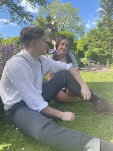 An image of a young man and woman sitting on the grass smiling