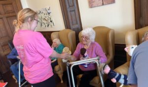 A young girl looking at soft toys with a care home resident, who is smiling