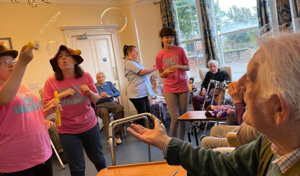 Young people blowing bubbles around the residents of a care home