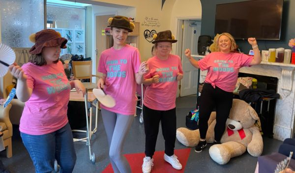 Cast members of Down To The Woods dancing in a care home wearing pink t shirts with the show logo on