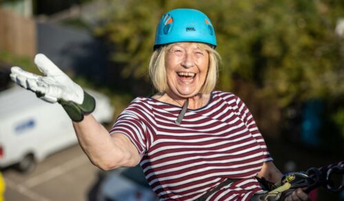 An image of a woman abseiling down The Courtyard building smiling and wearing a blue helmet