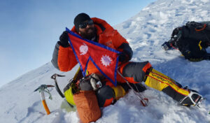 A man dressed in winter gear in the snow, holding a flag