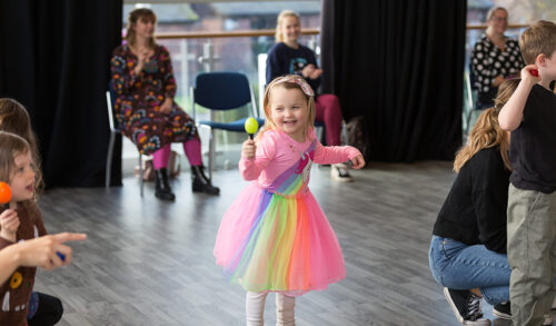 A little girl dancing in a multi coloured tutu